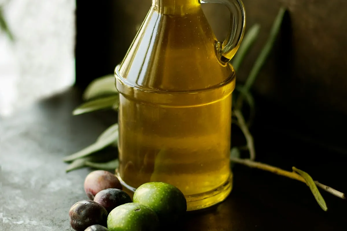 Carafe d’huile d’olive, olives fraîches et rameau d’olivier