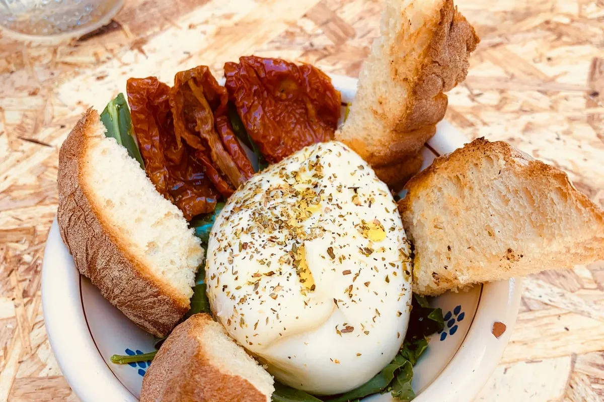 Burrata, tomates séchées et pain servis dans un plat